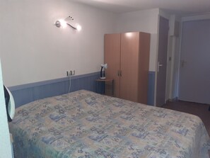 Un dormitorio con cama, armario, mesita de noche y lámpara de pared.