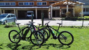 A hotel with a stone facade, a covered outdoor seating area, and a parking lot. - Hôtel du parc (Val-d'Aigoual)