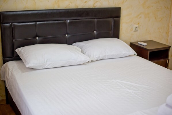 A neatly made bed with a dark headboard and white bedding.