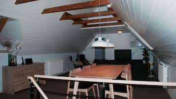 Ein Essbereich mit Holztisch und Stühlen, einer weißen Pendelleuchte und Blick auf eine Treppe.