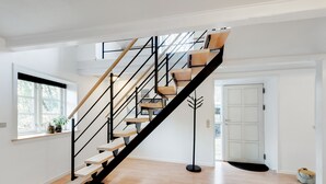 A modern staircase with wooden steps and black railings, leading to a second floor. - Adventure Park Apartments (Ringkobing)