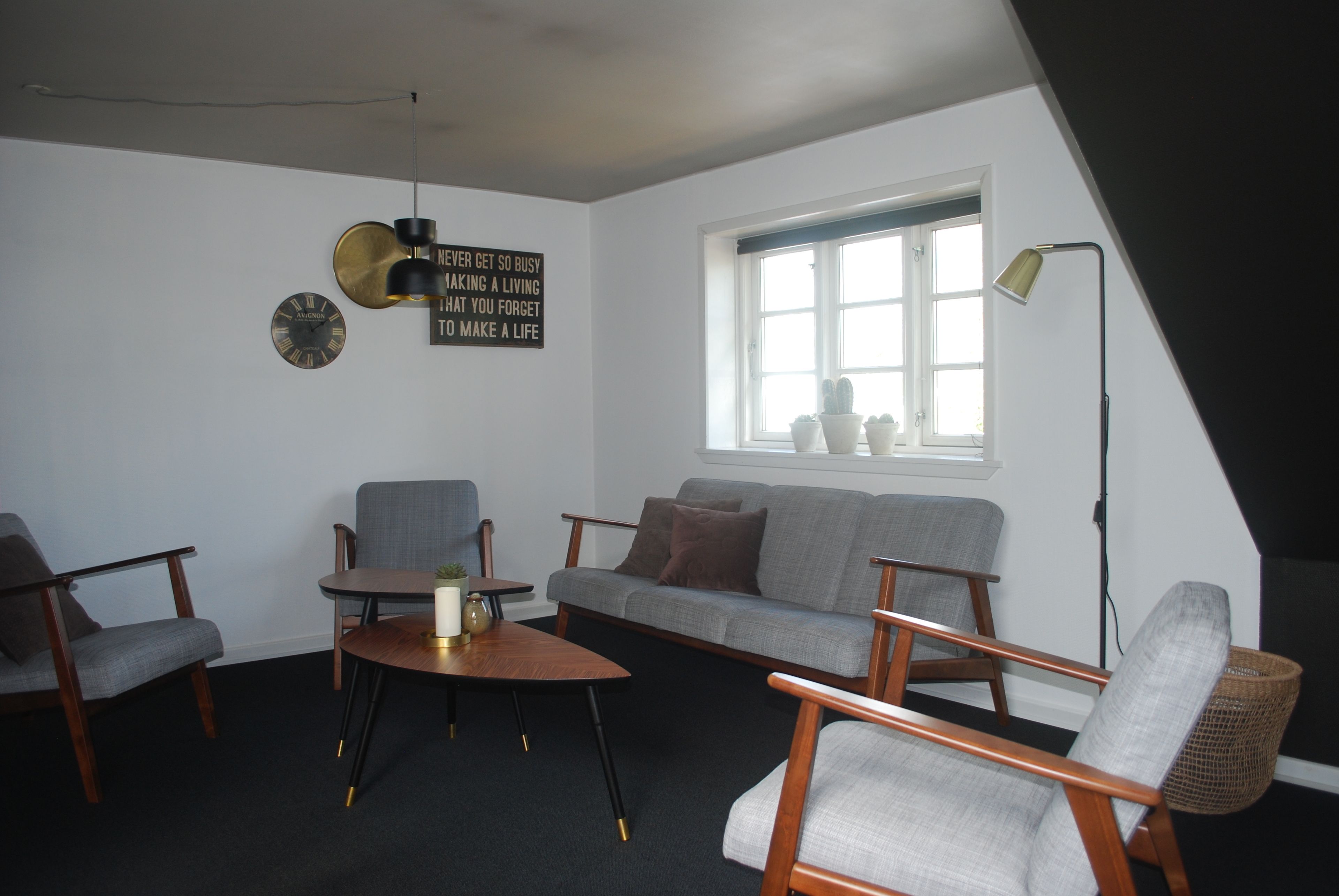 A living room with a sofa, chairs, a coffee table, a lamp, and a clock on the wall.