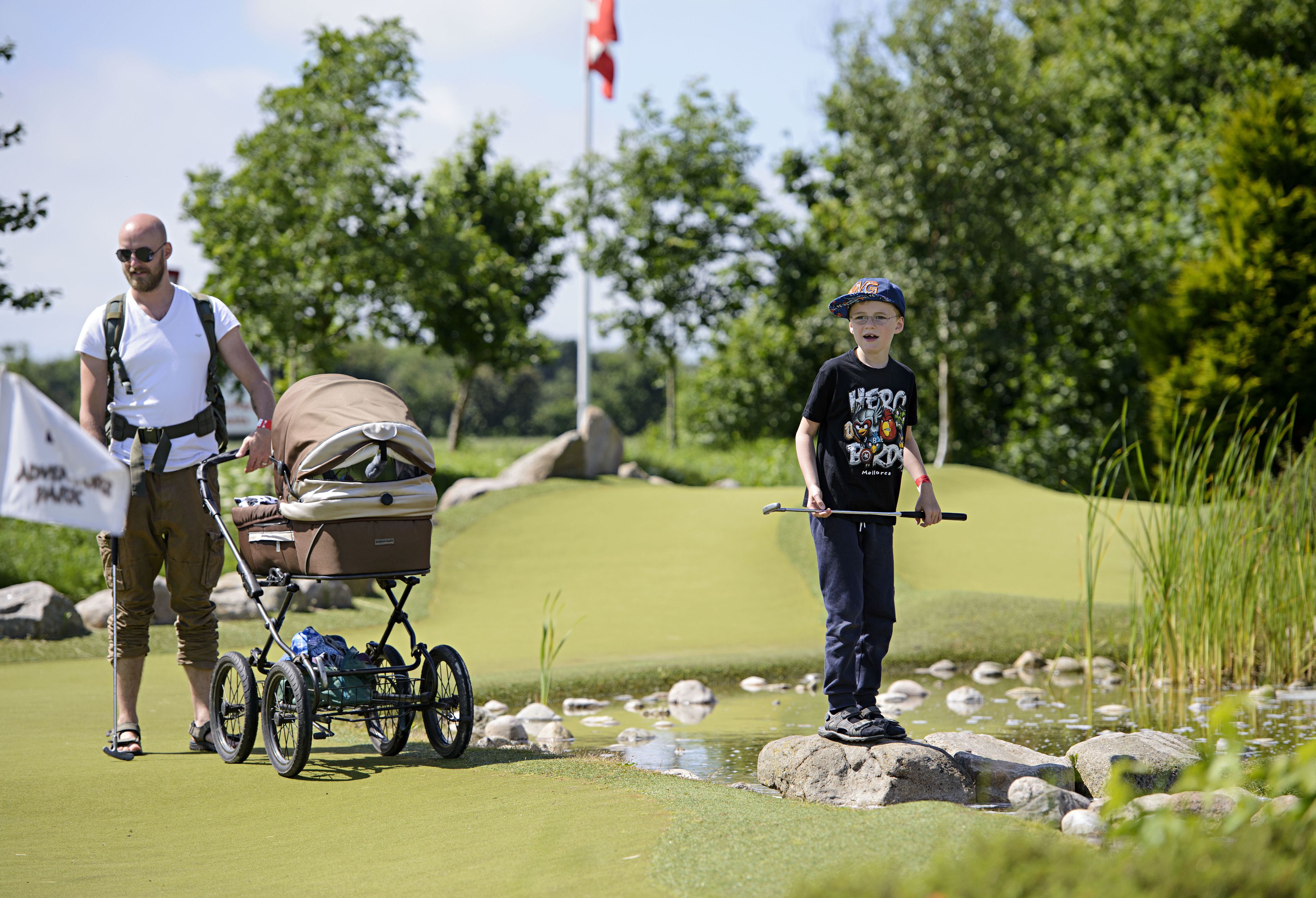 Ein Golfplatz mit einem Kinderwagen und einem Kind, das einen Golfschläger hält.