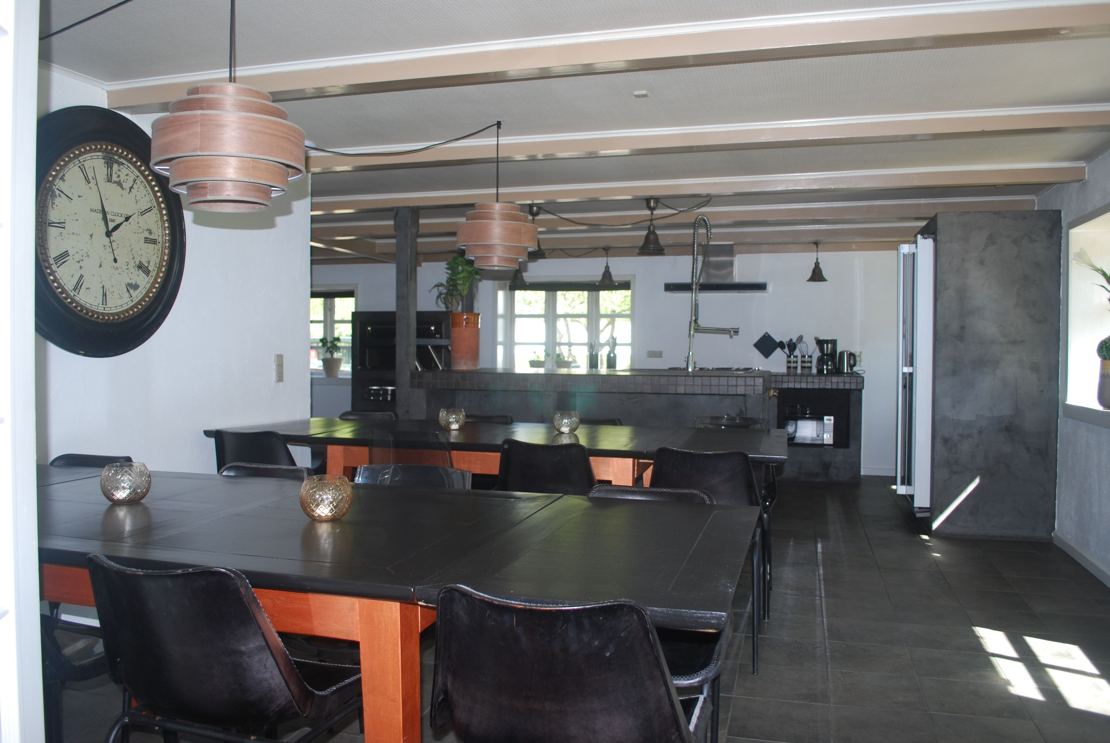 Una cocina moderna con una isla grande, iluminación colgante y un comedor con mesa y sillas.