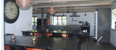 Una cocina moderna con una isla grande, iluminación colgante y un comedor con mesa y sillas.