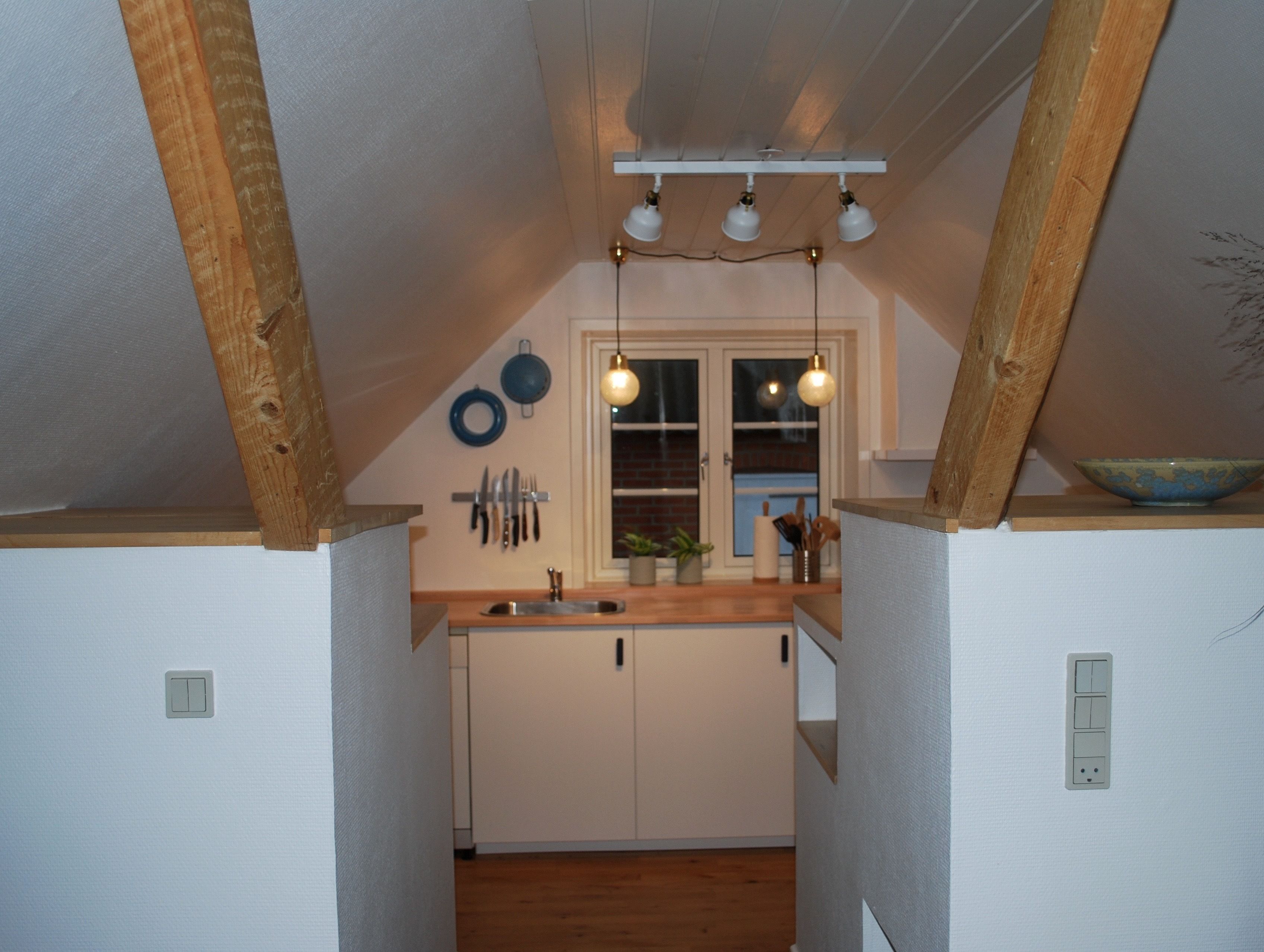 Una cocina con vigas de madera, una ventana y un lavabo.