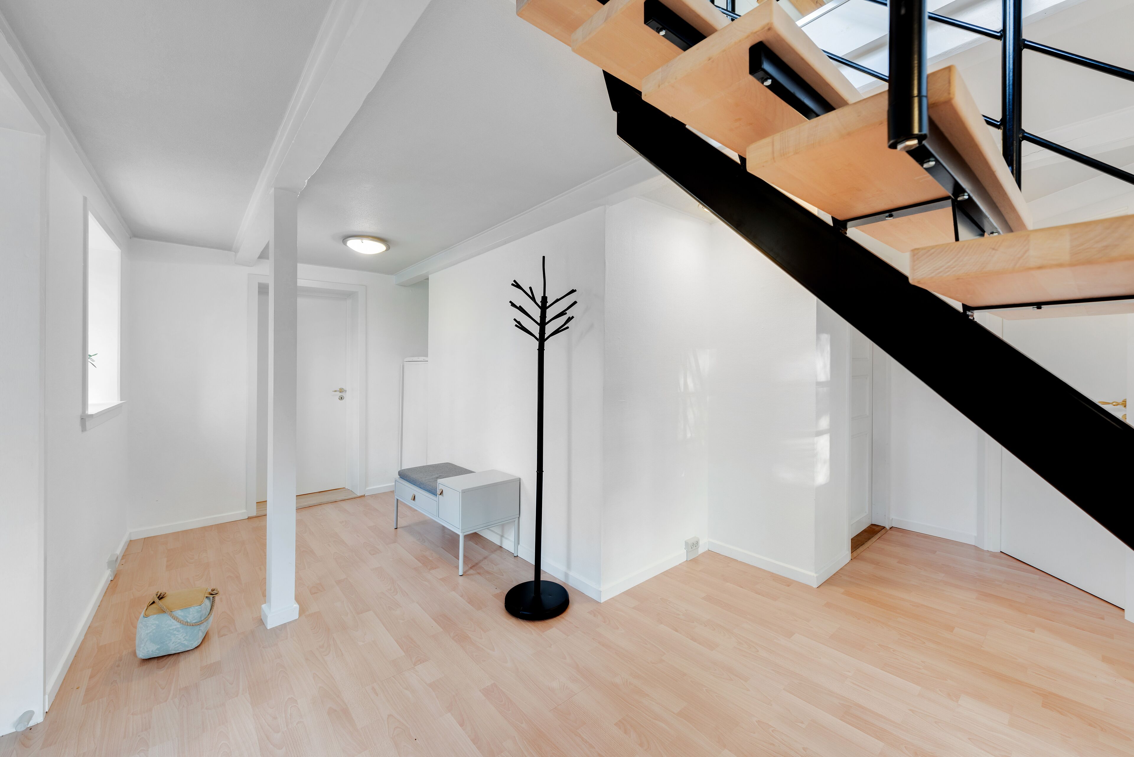 A modern interior with a staircase, a coat rack, and a bench.