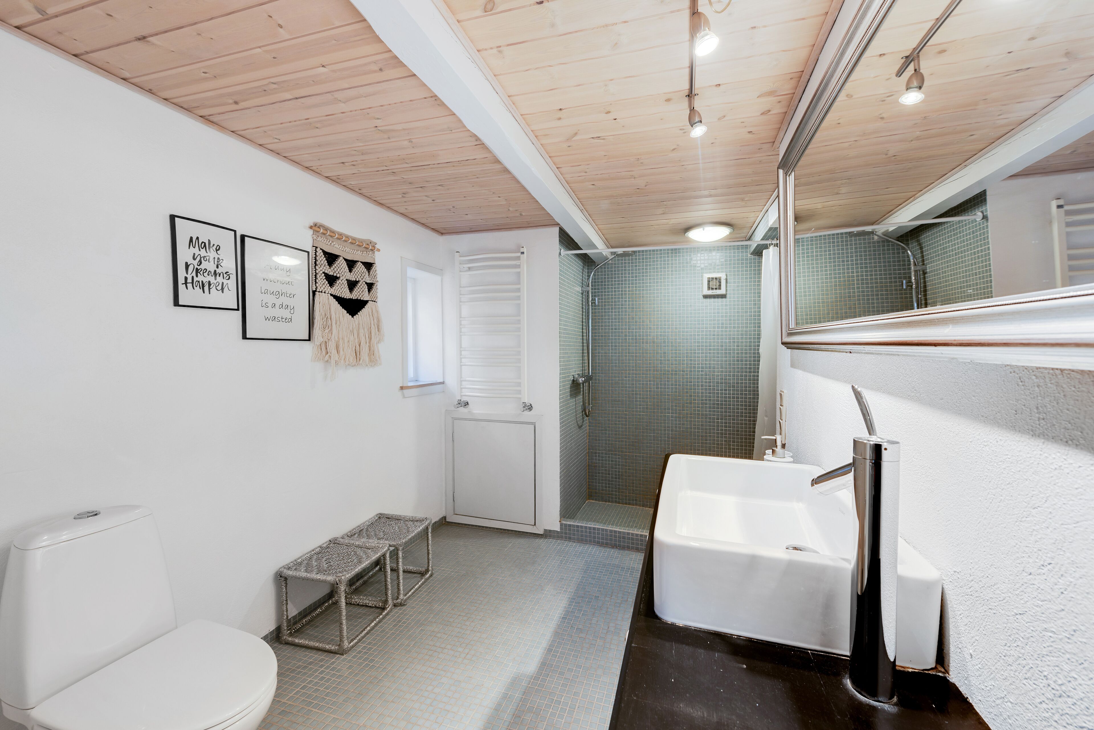 A bathroom with a toilet, sink, and shower. There are framed motivational quotes on the wall.