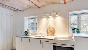 A modern kitchen with white cabinets, a built-in oven, a sink, and a window with a view. - Adventure Park Apartments (Ringkobing)