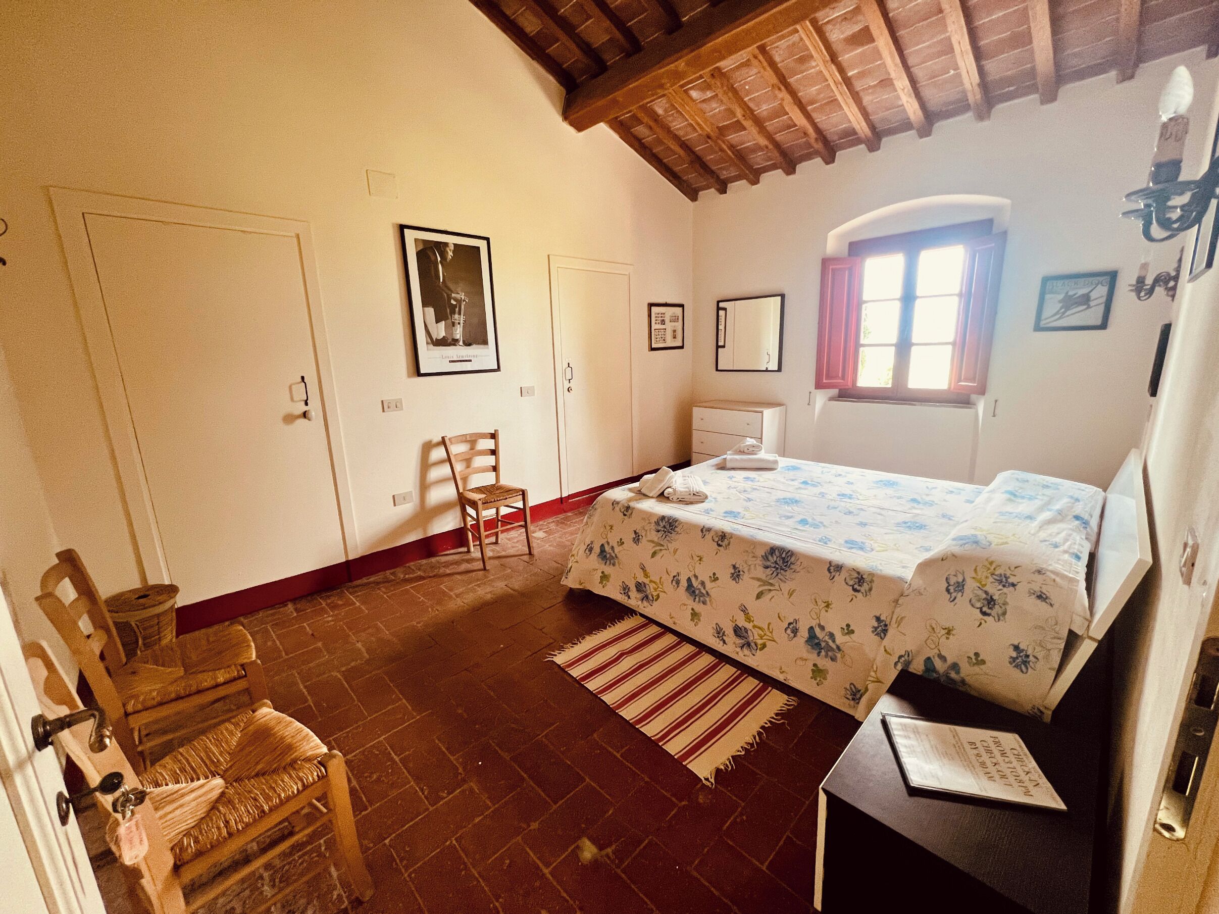 A bedroom with a bed, a chair, a desk, a window, and a door.