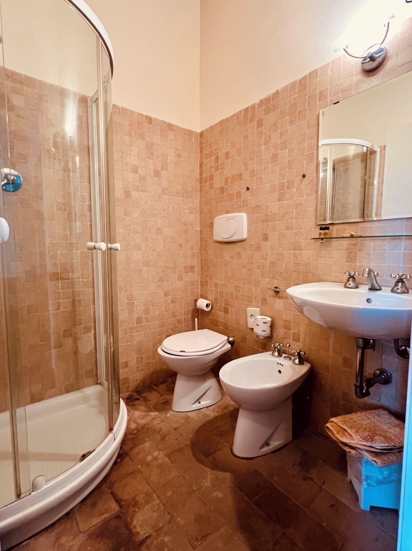 Een badkamer met een douchecabine van glas, twee toiletten, een wastafel en een spiegel.