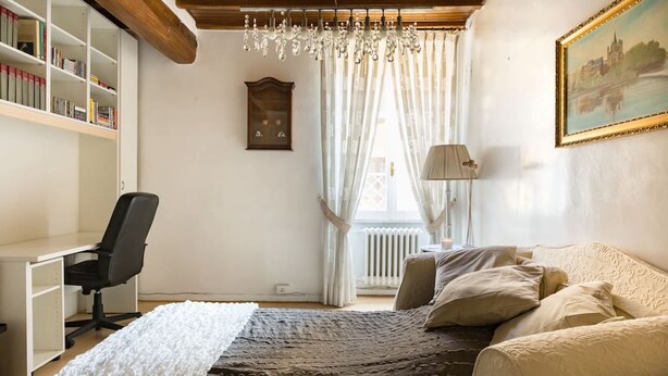 A bedroom with a bed, a desk, a chair, a bookshelf, a radiator, and a painting on the wall. - Via Laurina 40 Apartment (Rome)