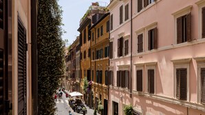 Una stretta via fiancheggiata da edifici tradizionali, alcuni con persiane, e qualche passante.
