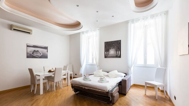 Una camera d'albergo con un letto, una scrivania, sedie e opere d'arte alle pareti.
