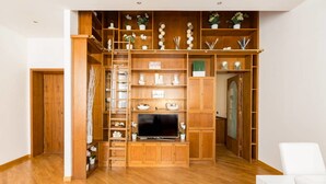 Una camera spaziosa con un'unità di intrattenimento in legno, mensole a muro e una TV a schermo piatto.