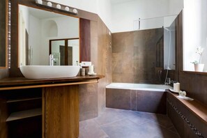 A modern bathroom with a large vessel sink, a freestanding bathtub, and a large mirror. - A World Apart - Trevi Apartments (Rome)
