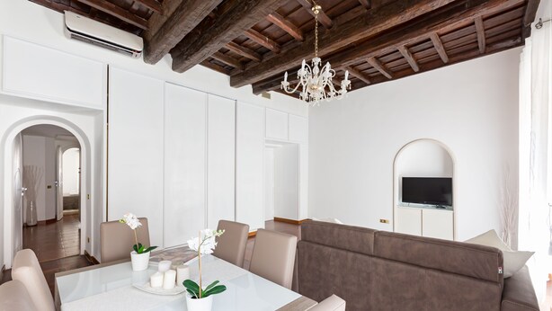 A modern living room with a dining table, sofa, and TV. - A World Apart - Trevi Apartments (Rome)