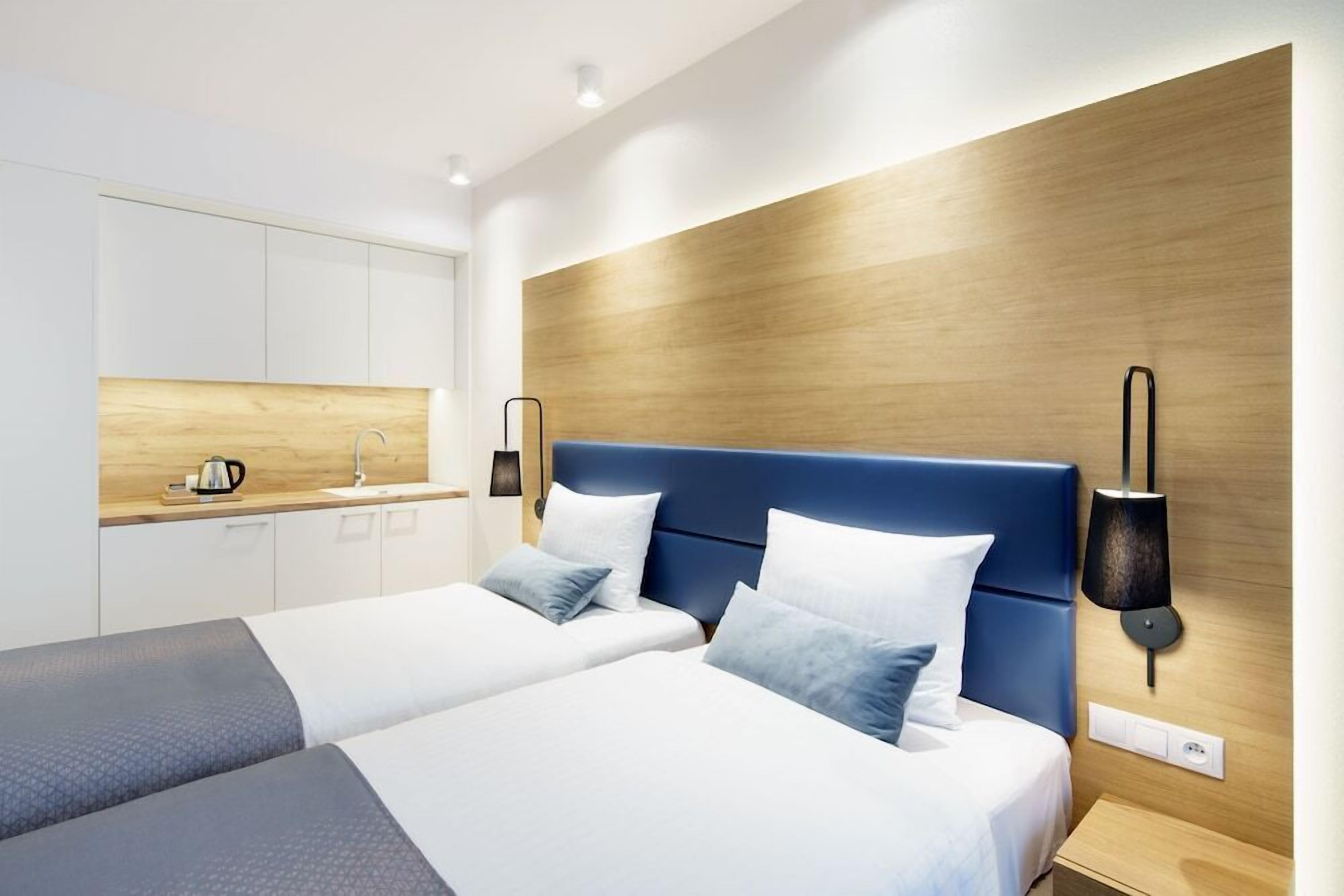 A modern hotel room with a large bed, a small desk, and a wooden accent wall.