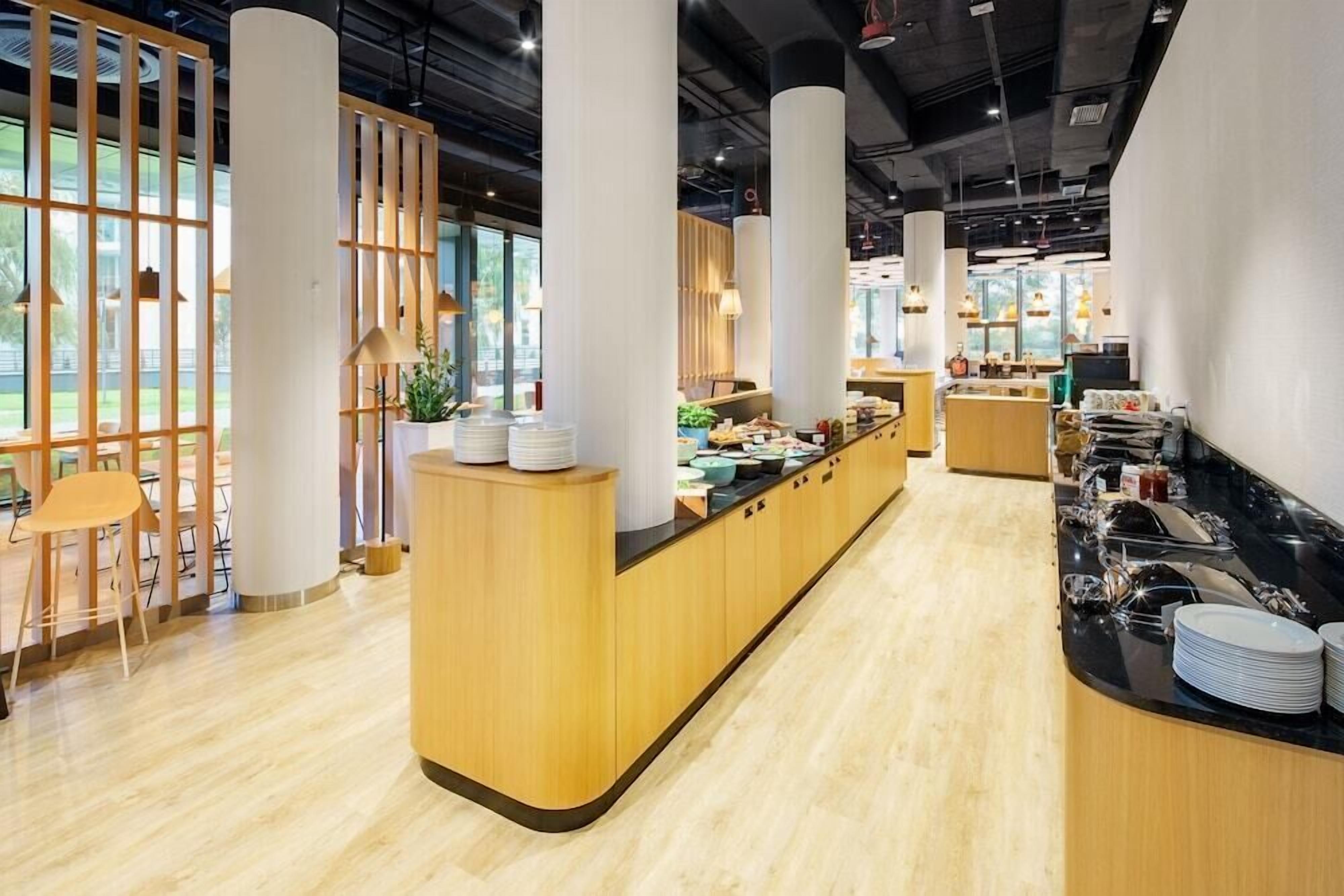 Ein modernes Café mit Holztresen, Sitzgelegenheiten und großen Fenstern.