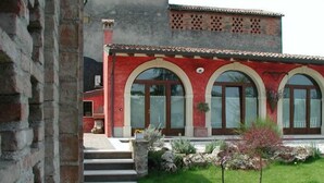 A building with a red facade, arched windows, and a stone pathway leading to the entrance. - Agriturismo Gian Galeazzo Visconti (Valeggio sul Mincio)