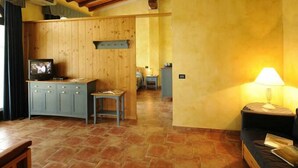 A cozy room with a wooden ceiling, a small kitchen area, a sofa, and a lamp. - Agriturismo Gian Galeazzo Visconti (Valeggio sul Mincio)