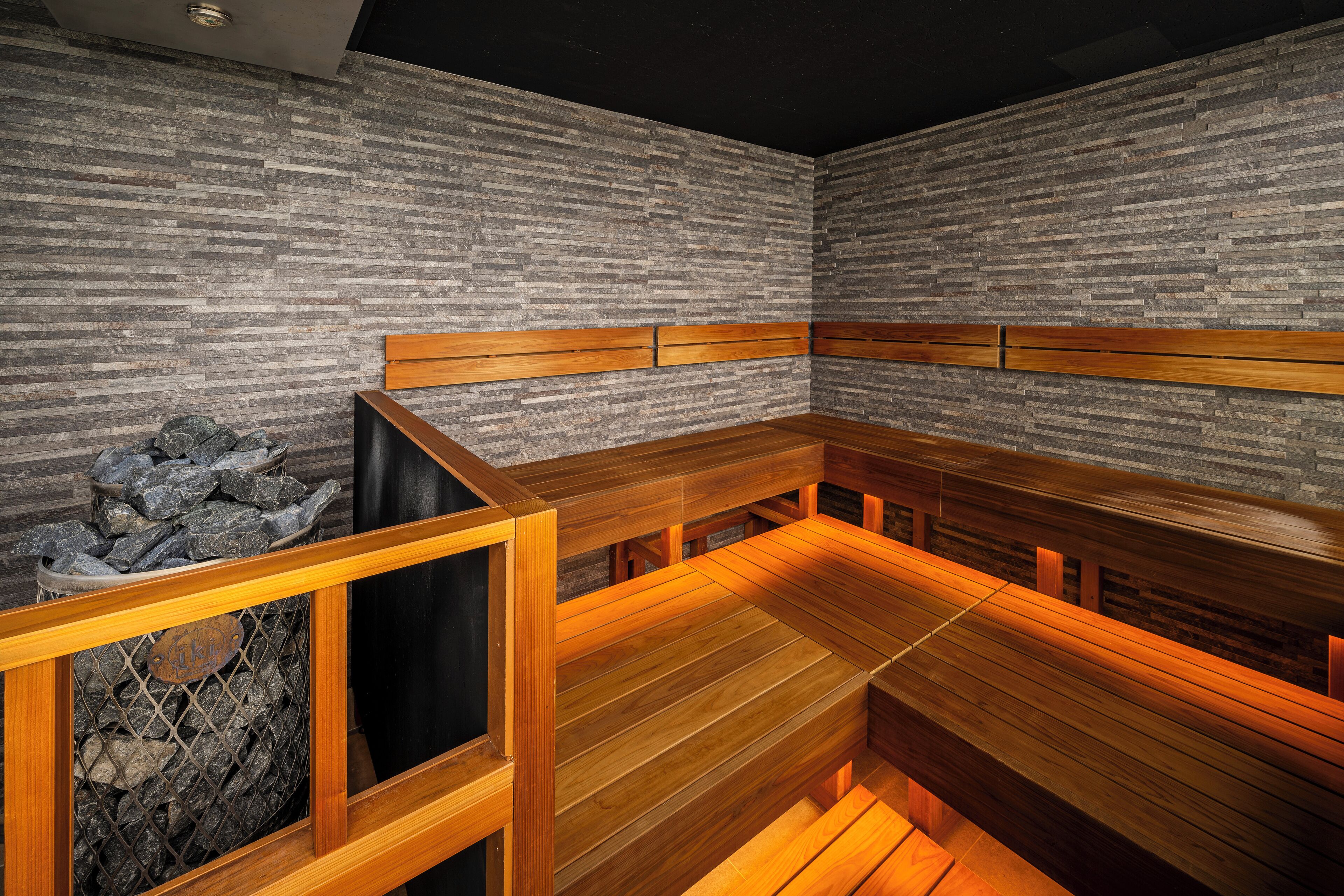 A sauna with wooden benches and a stone wall.