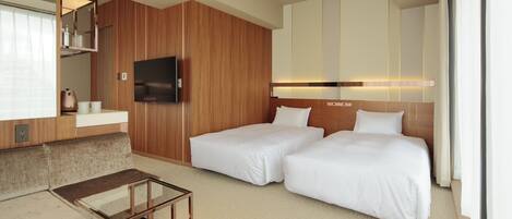 Una habitación de hotel con dos camas, un sofá, un televisor y un minibar.
