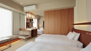 A hotel room with two beds, a sofa, a desk, and a kitchenette.