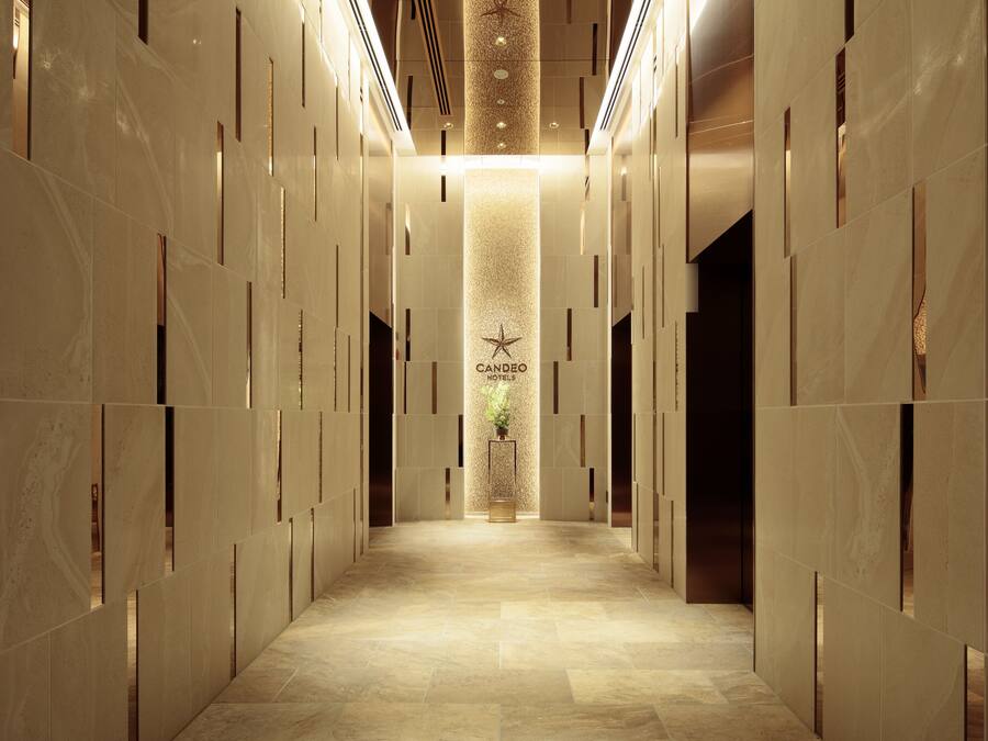 Un couloir d’hôtel avec une colonne centrale, un logo en forme d’étoile et une plante.