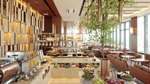 Een moderne hotellobby met een buffetgedeelte, zitplaatsen en een groot raam met uitzicht op de stad.