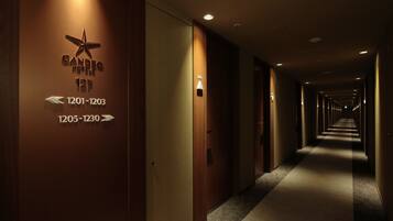 A hotel corridor with directional signs indicating room numbers 1201-1203 and 1205-1230.