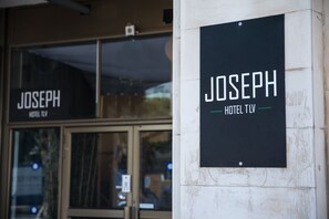 A sign for 'JOSEPH HOTEL TV' mounted on a wall. - Joseph Hotel TLV (Tel Aviv)