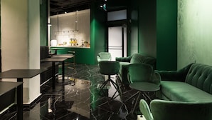 A modern interior with a green sofa, a dining area, and a kitchen. - Joseph Hotel TLV (Tel Aviv)