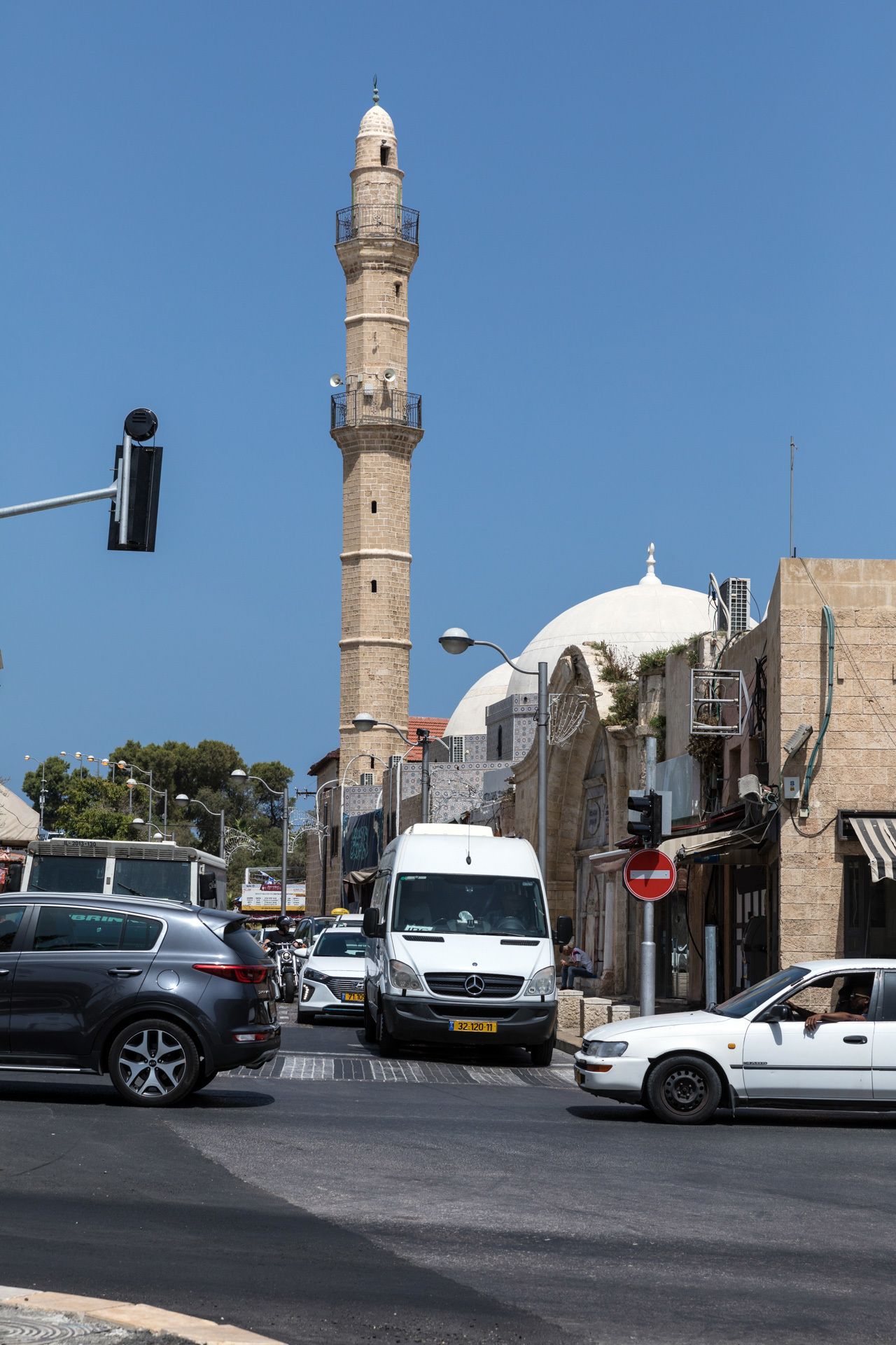 A street with a tall minaret and a mosque with a dome.