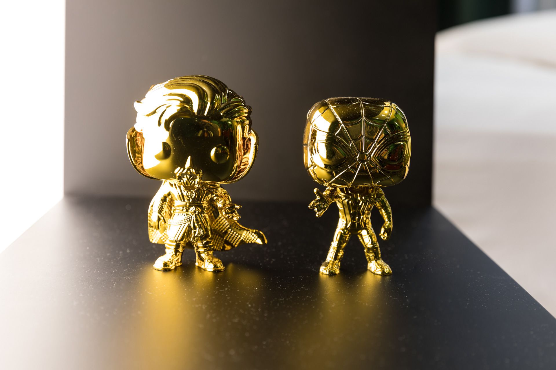 Duas estatuetas douradas sobre uma superfície preta espelhada.