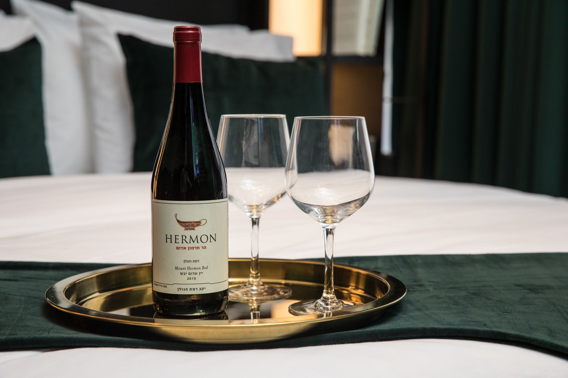 A bottle of Mount Hermon Red wine on a tray with two glasses.