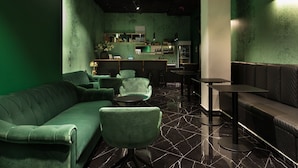 A green-themed bar area with a sofa, chairs, and a bar counter. - Joseph Hotel TLV (Tel Aviv)