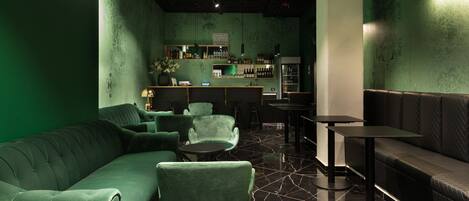 Un espace bar décoré dans des tons verts, avec un canapé, des fauteuils et un comptoir.