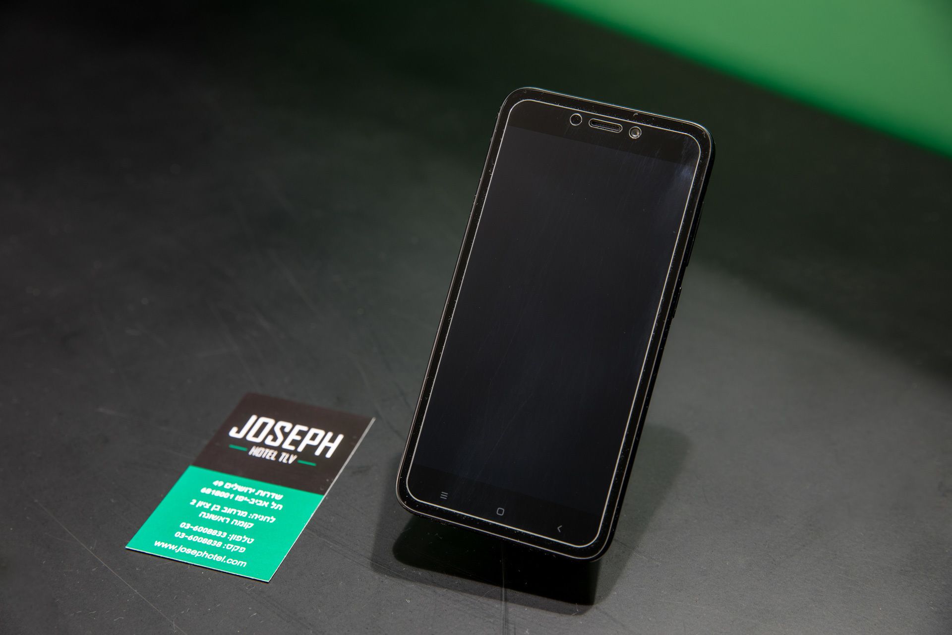 A smartphone on a stand with a business card beside it.