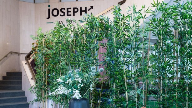 A lobby with a staircase, a brown chair, and a wall with the text "JOSEPH'S". - Joseph Hotel TLV (Tel Aviv)