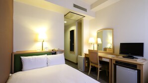 A hotel room with a bed, desk, chair, television, and a small refrigerator.