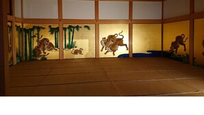 A tatami mat room with traditional Japanese sliding doors depicting tiger scenes.