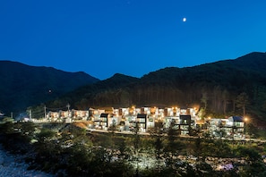 Un hôtel moderne composé de plusieurs bâtiments, entouré de montagnes et d’arbres.