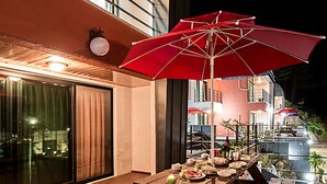 An outdoor dining area with a grill, wooden tables, and a red umbrella. - Yeoninsan Hot Spring Resort (Gapyeong)