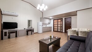 A modern living room with a flat-screen TV, a coffee table, a sofa, and a kitchen area in the background. - Yeoninsan Hot Spring Resort (Gapyeong)
