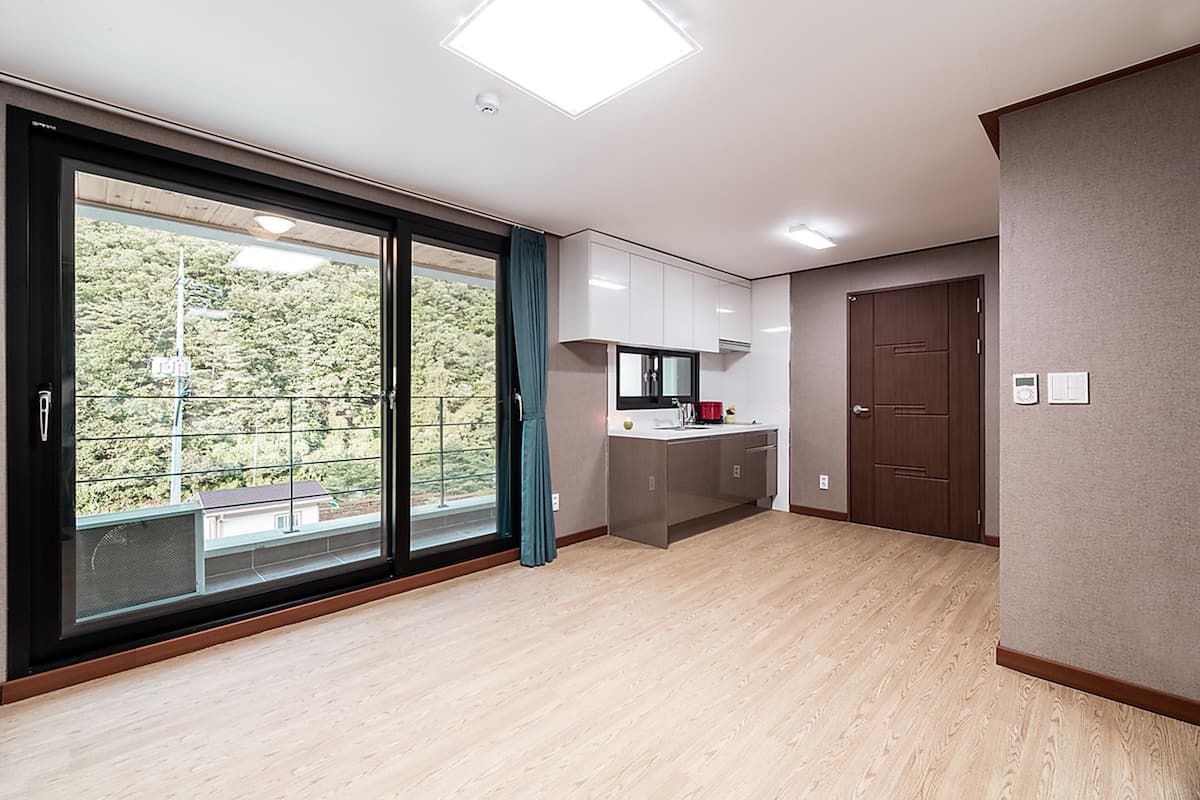A modern hotel room with a large sliding glass door, a kitchenette, and a view of the outdoors.