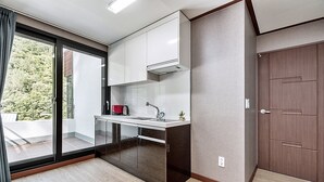 A modern kitchen with a sliding glass door leading to a balcony, a built-in oven, and a small sink. - Yeoninsan Hot Spring Resort (Gapyeong)