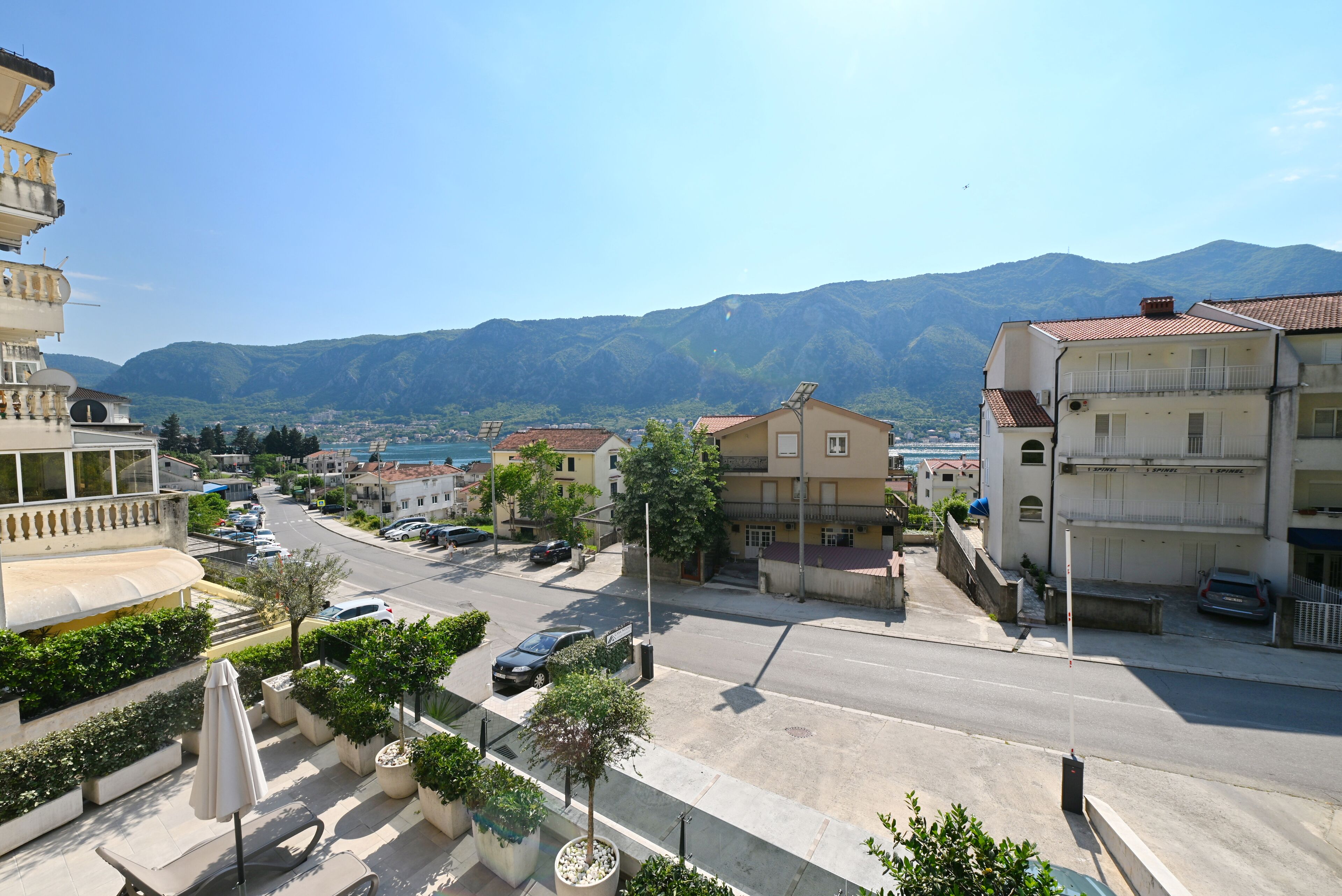 A street view with buildings, a clear sky, and mountains in the background.