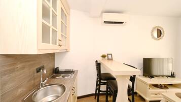 Una cocina compacta con fregadero, estufa y un pequeño comedor con sillas y mesa.