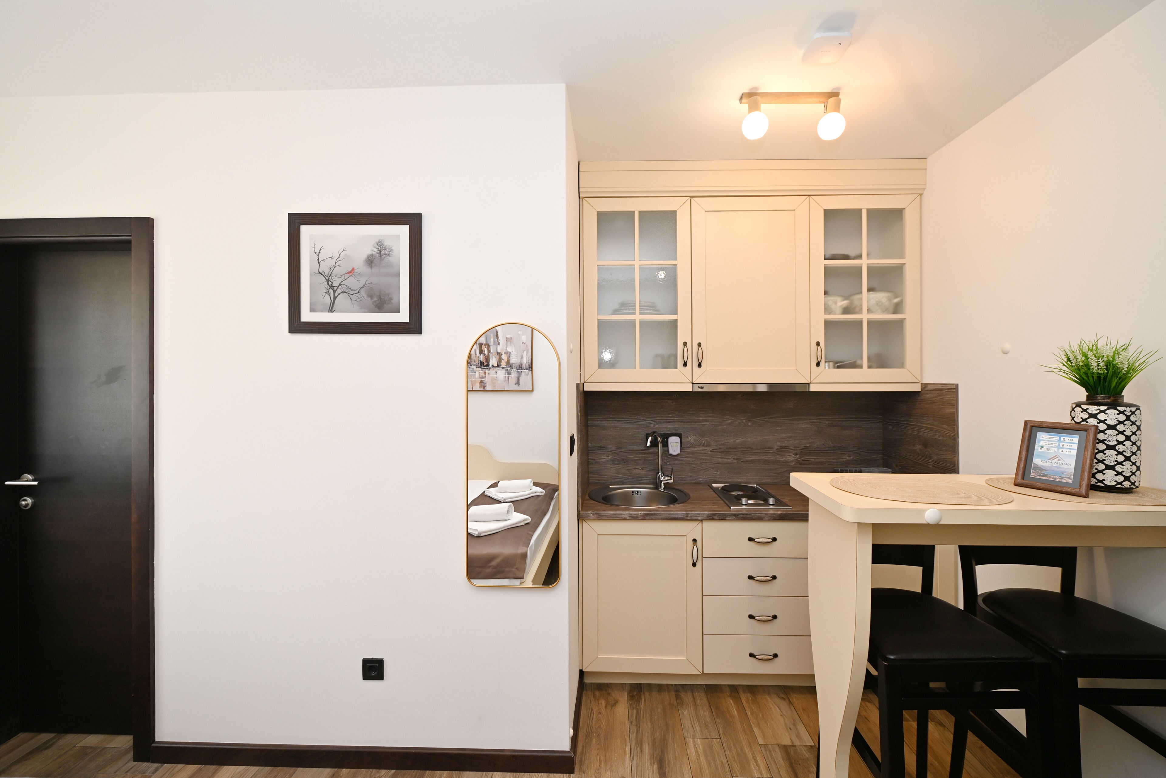 A compact kitchen with a sink, cabinets, and a dining area with a table and chairs.